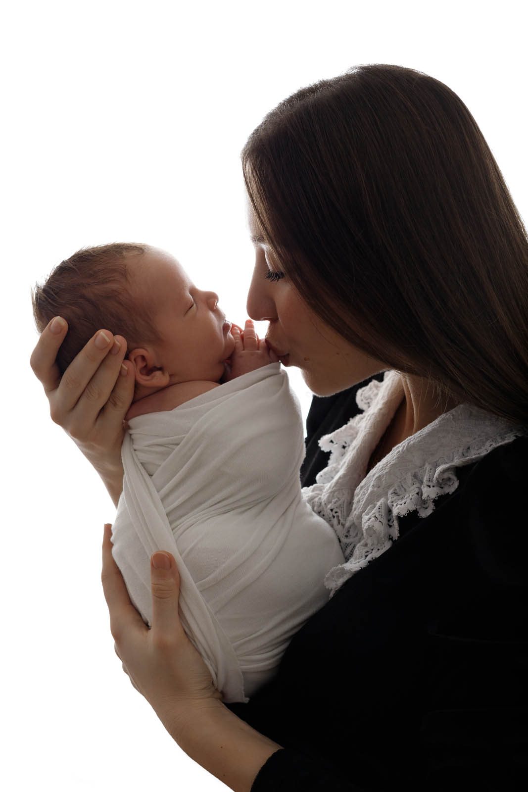Mother kissing her newborn in soft backlight — family photography Tbilisi