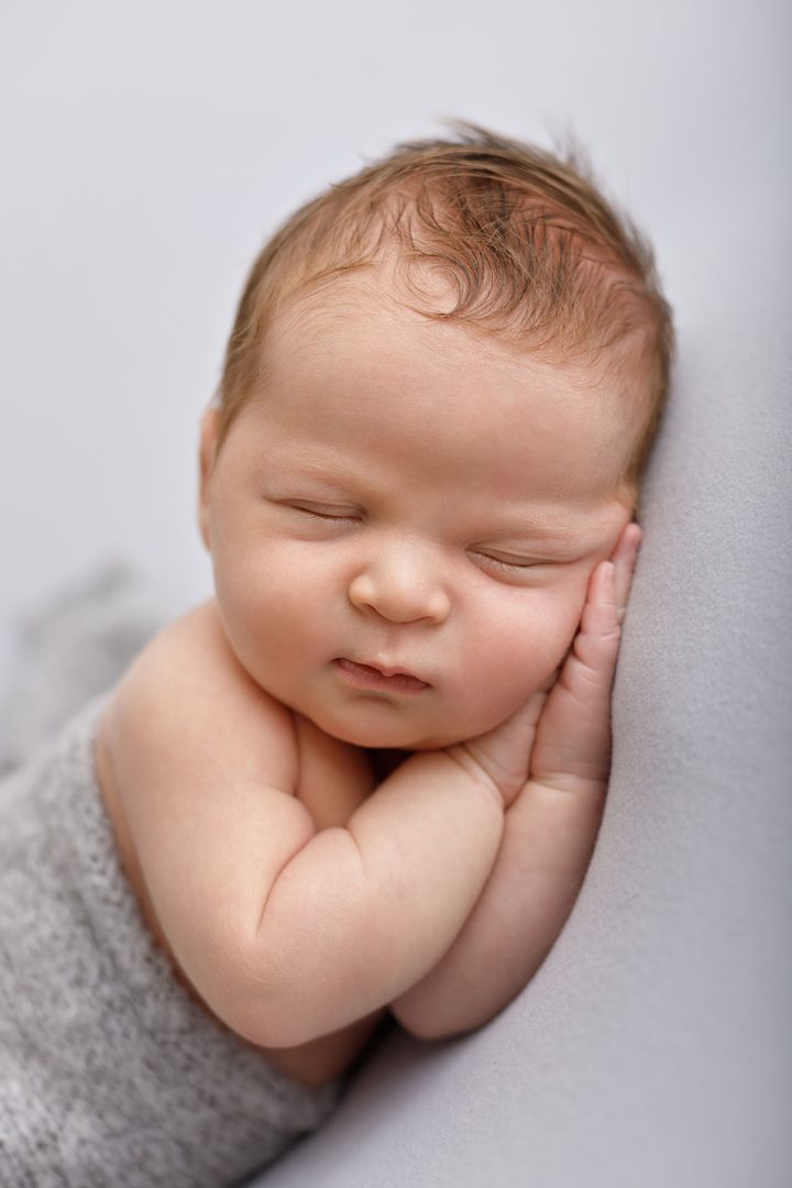 Newborn baby posed gently on a blush backdrop — premium studio session in Tbilisi