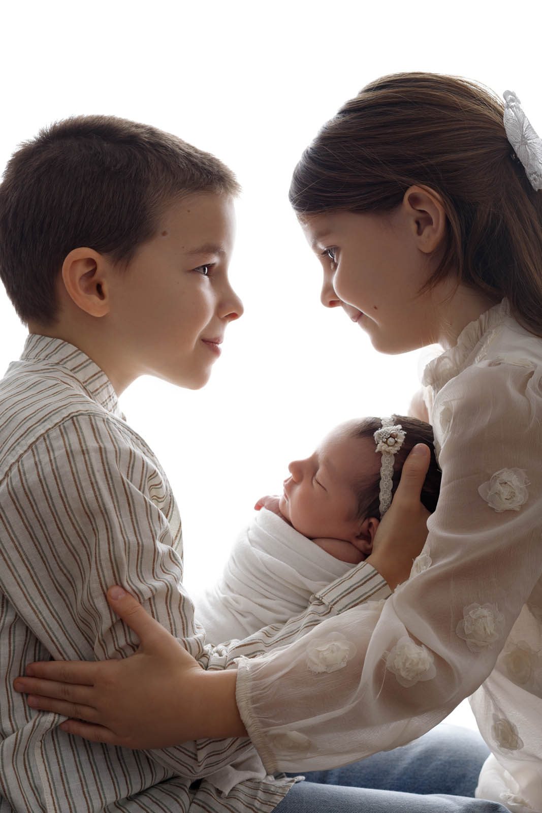 Siblings holding their newborn on a red backdrop — Studio Muffin Tbilisi